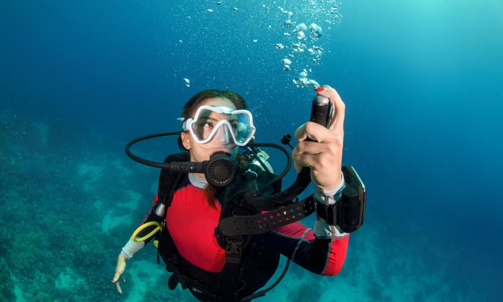 A diver holding up the BCD inflator hose