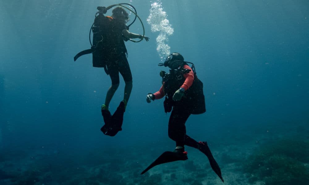 Two divers in open water, with bubbles rising from one of them